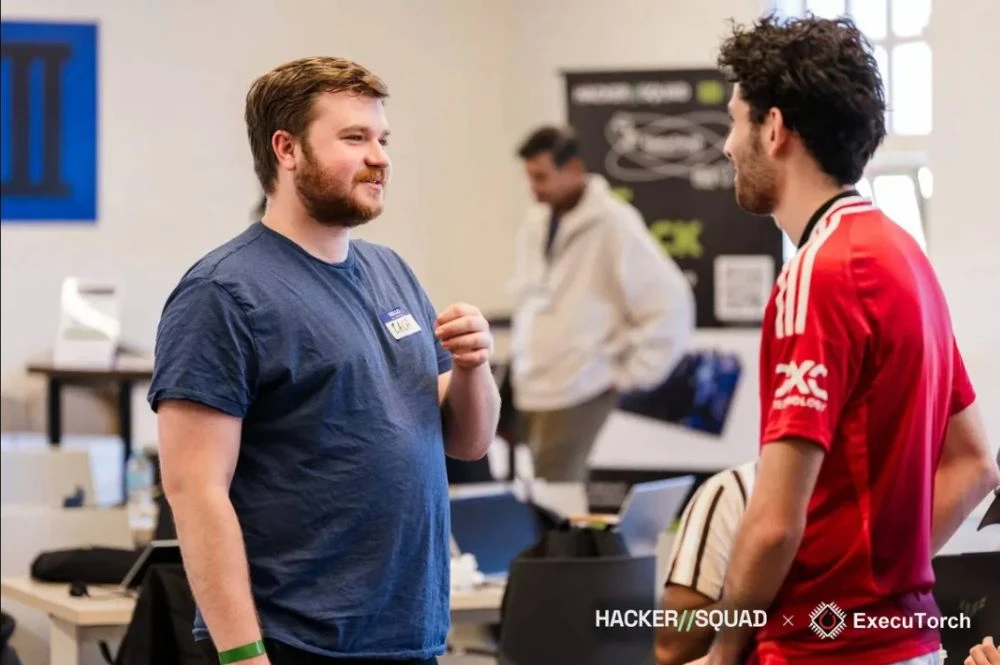 Zach in a blue shirt talking with another participant at the hackathon