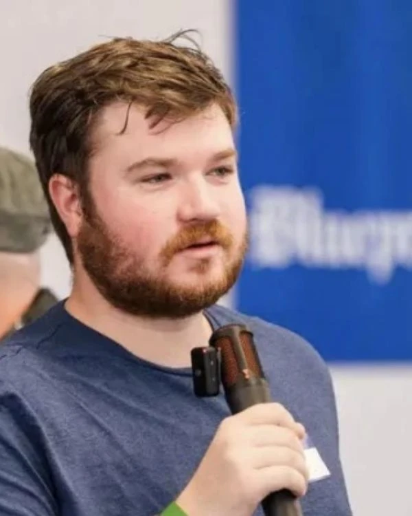 Zachary Lafer speaking at the hackathon, wearing a blue shirt